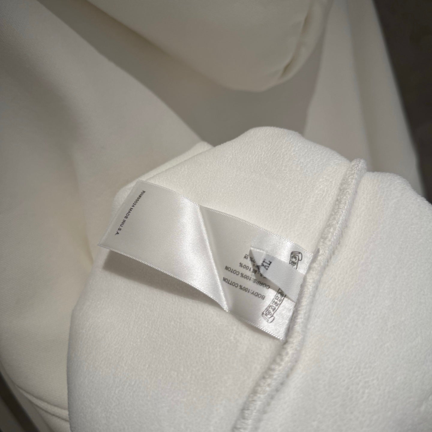 Close-up of white hoodie tag stitched near the zipper seam
