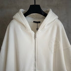White zip-up hoodie with hood, silver-tone zipper and textured oval chest patch