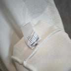 White hoodie sleeve with attached fabric tag near the cuff