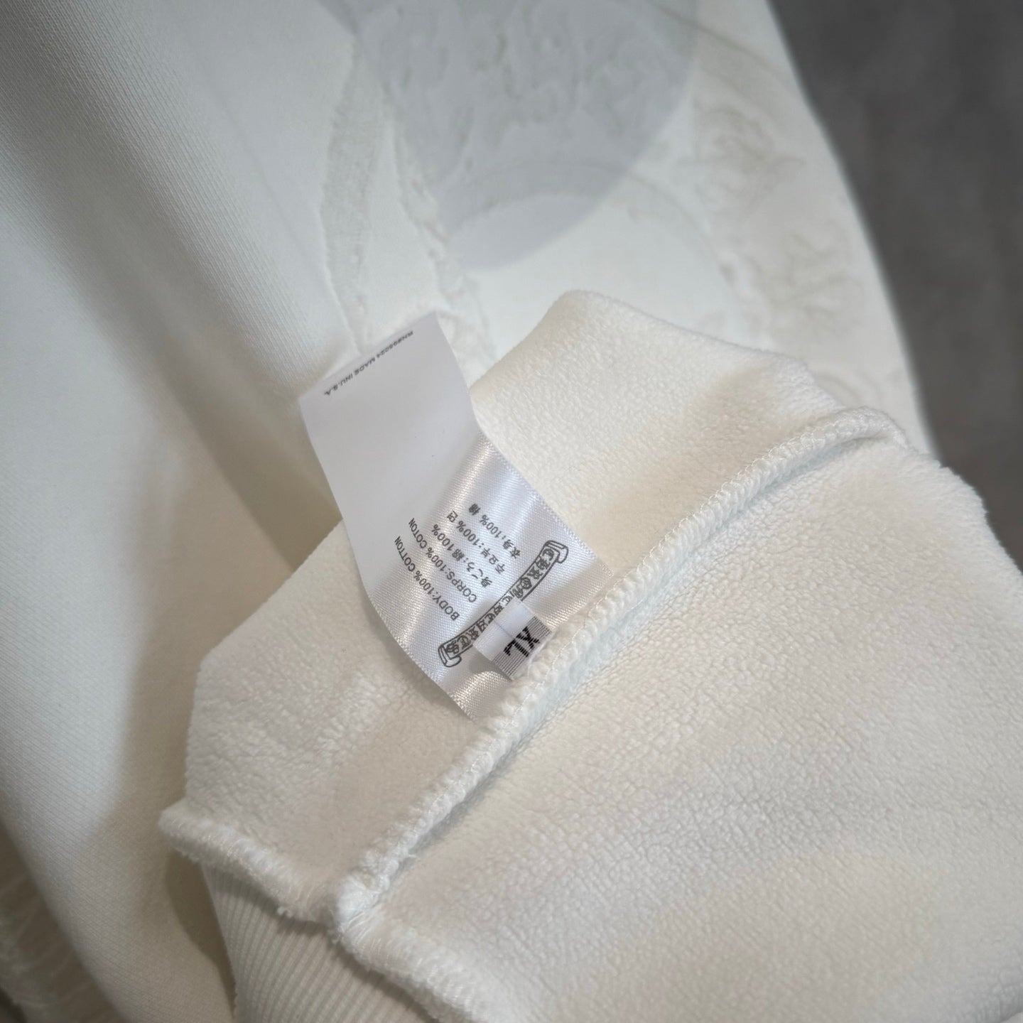 White hoodie sleeve with attached fabric tag near the cuff