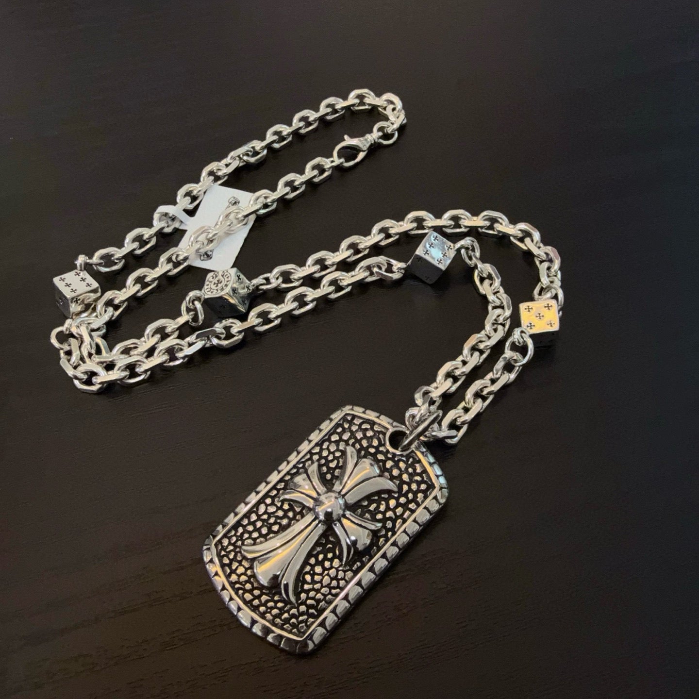 Silver-tone chain necklace with large rectangular cross pendant and charm details