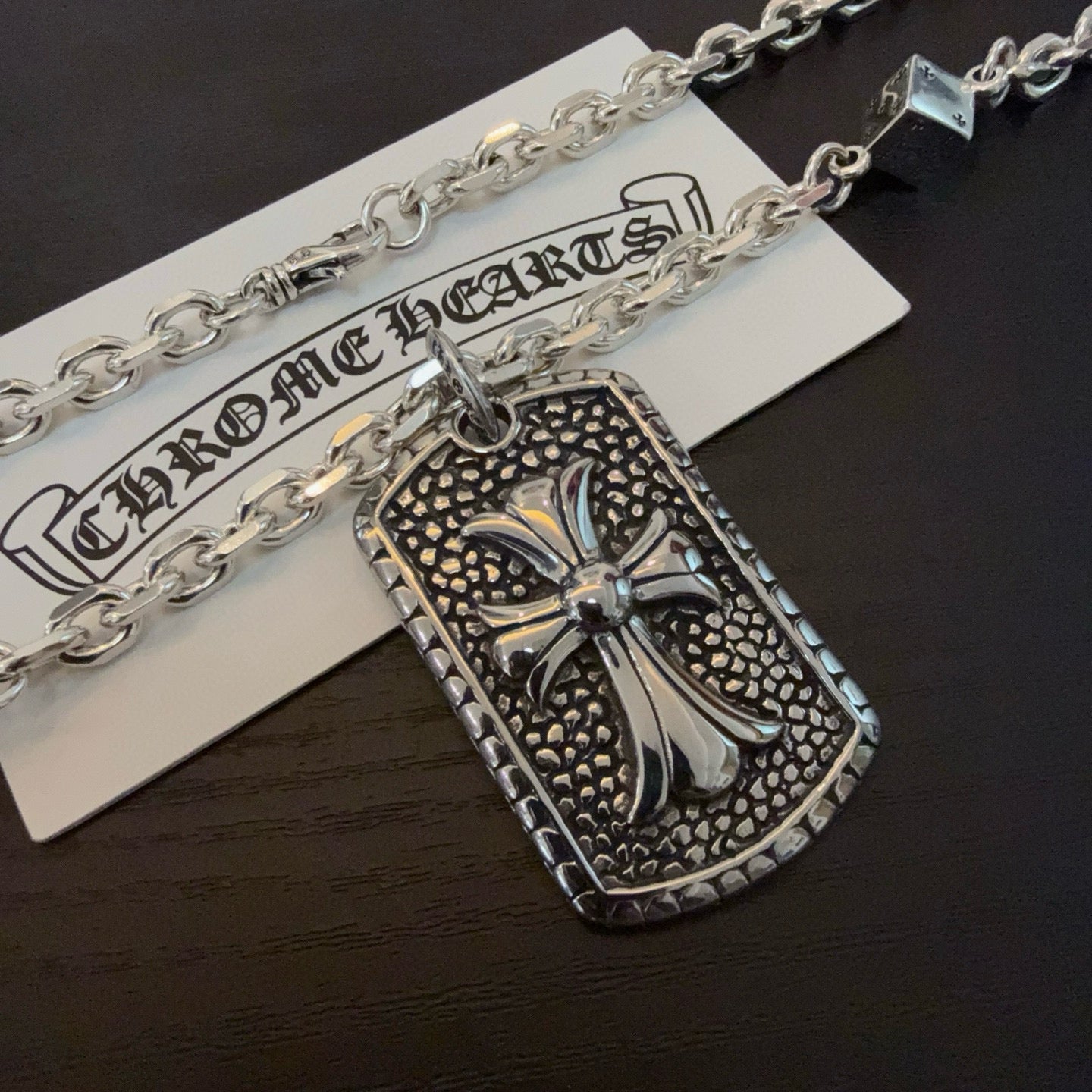 Rectangular silver-tone cross pendant on a chain with small decorative links