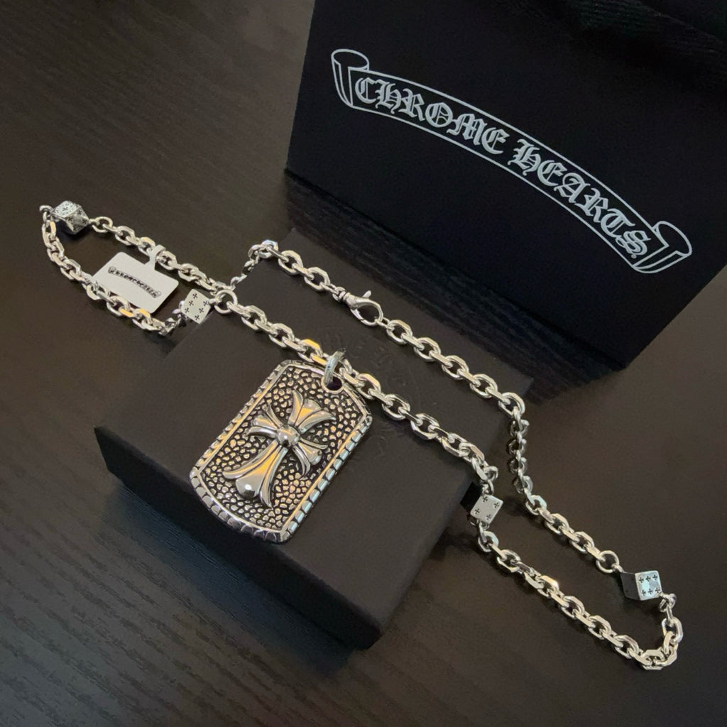 Silver-tone chain necklace with rectangular cross pendant and small charm accents