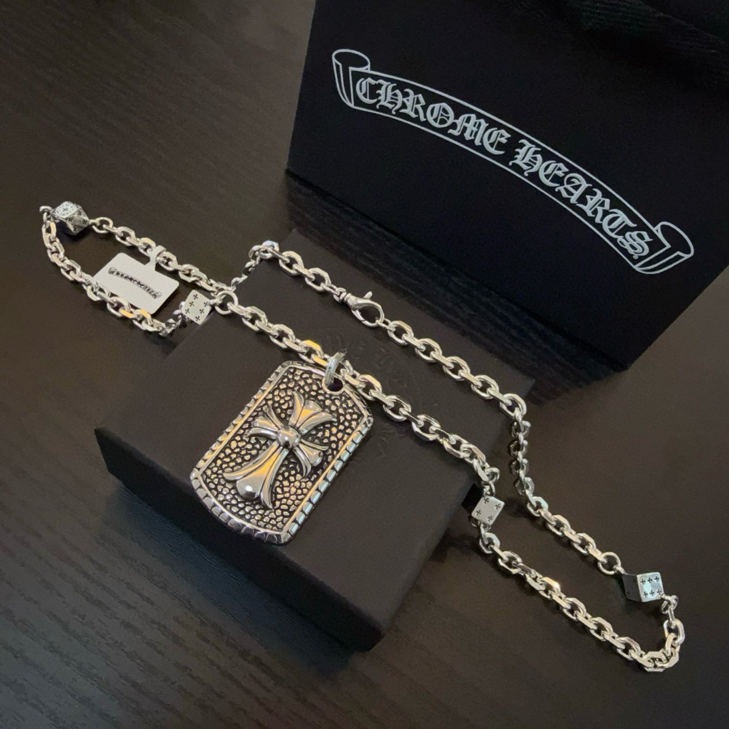 Silver-tone chain necklace with rectangular cross pendant and small charm accents