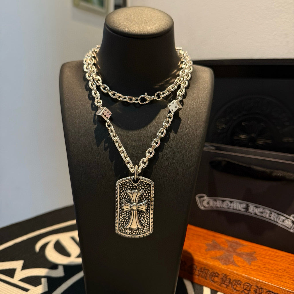 Silver-tone chain necklace with rectangular cross pendant on a dark display bust