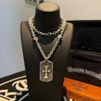 Silver-tone chain necklace with rectangular cross pendant on a dark display bust