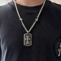 Silver-tone chain necklace with rectangular cross pendant worn on a dark crewneck shirt