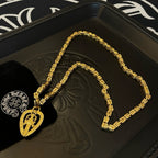 Gold-tone chain necklace with round teardrop pendant on black tray