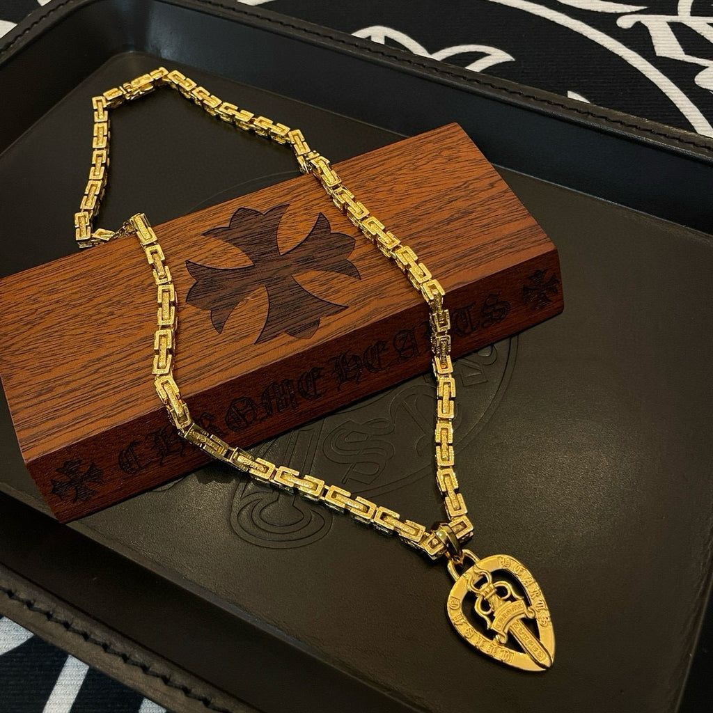 Gold-tone chain necklace with teardrop pendant charm on black tray
