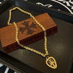 Gold-tone chain necklace with teardrop pendant charm on black tray