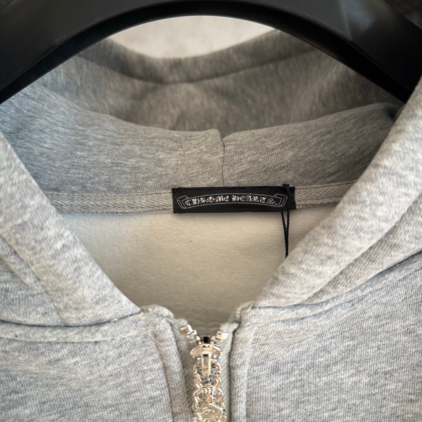 Light gray hoodie neckline with front zipper and black brand label
