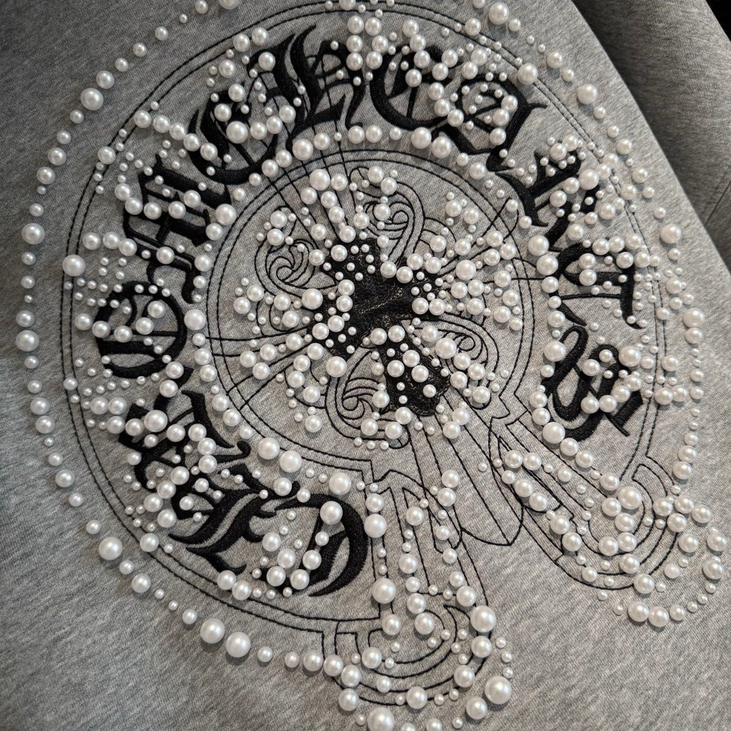 Light gray hoodie front jeweled circular emblem with pearl-like bead details