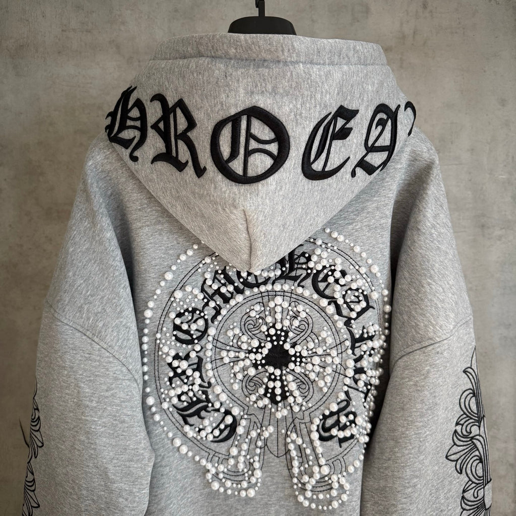 Light gray hoodie back with large black lettering and jeweled circular emblem