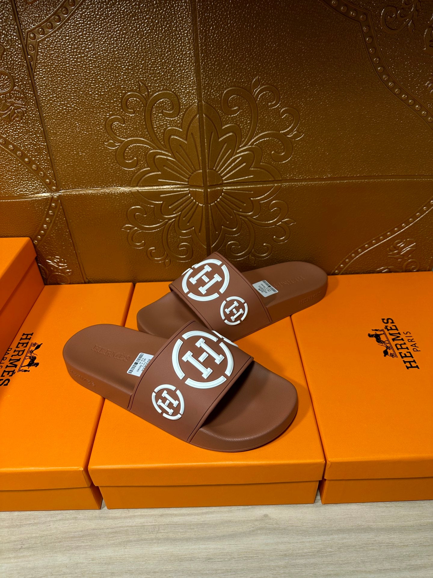 Brown slide sandals with white logo straps, close pair view