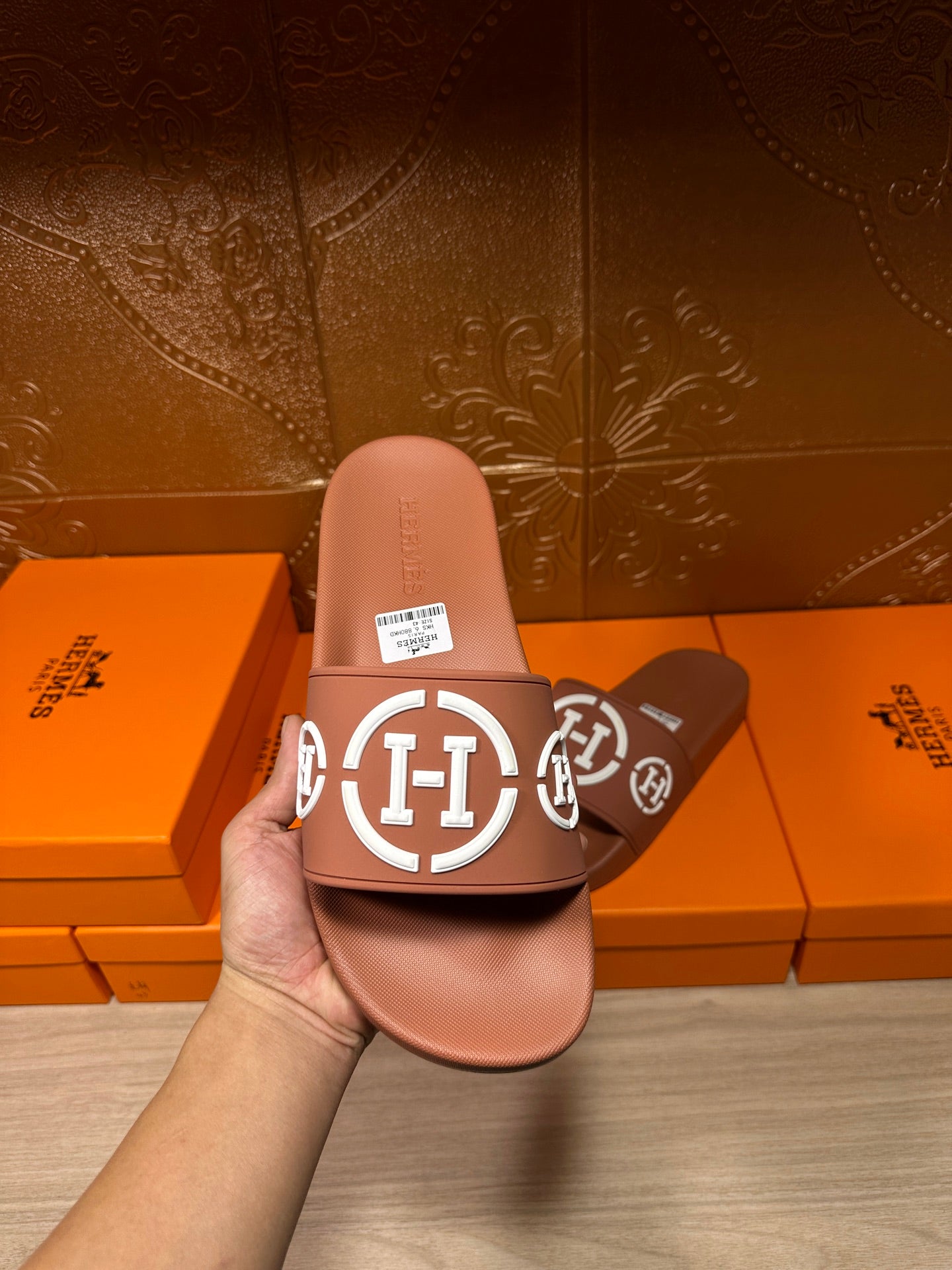 Light pink slide sandals with white logo strap, close-up held view