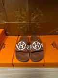 Brown slide sandals with white logo straps, pair view