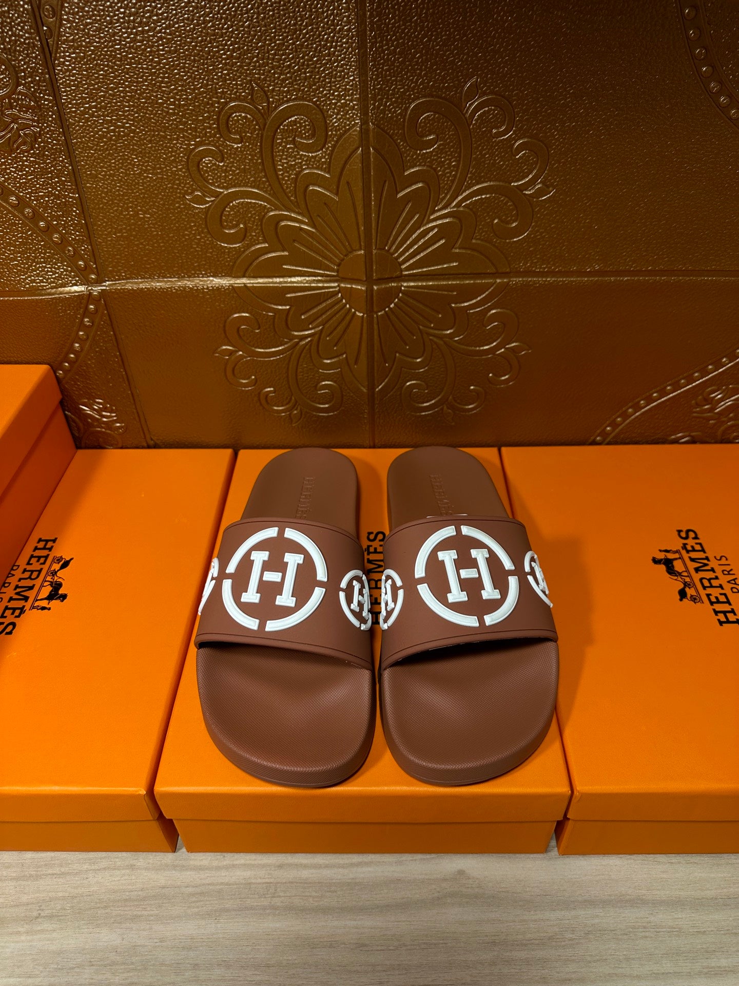 Brown slide sandals with white logo straps, pair view
