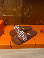 Brown slide sandals with white logo straps, angled pair view