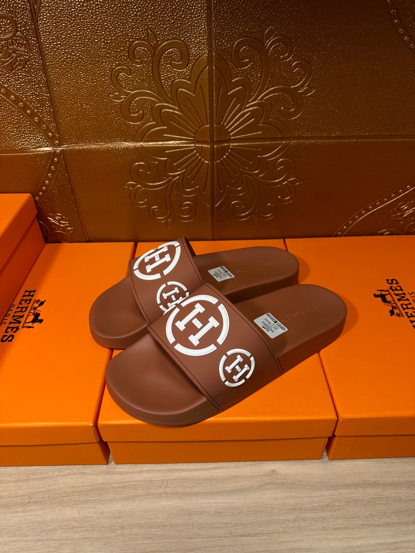 Brown slide sandals with white logo straps, angled pair view