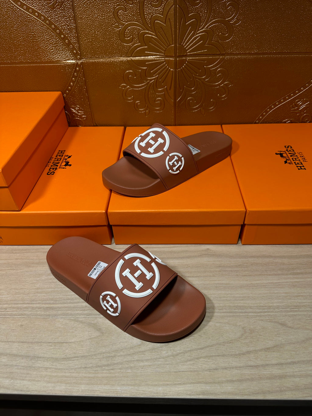 Brown slide sandals with white logo straps, side-by-side pair view
