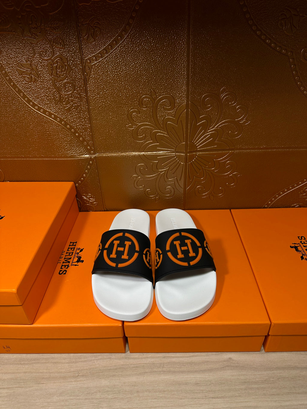 Slide sandal with black strap and orange logo detail, white footbed and sole
