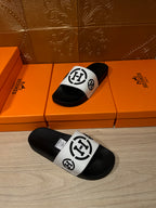 Pair of black slide sandals with white logo straps, one sandal upside-down