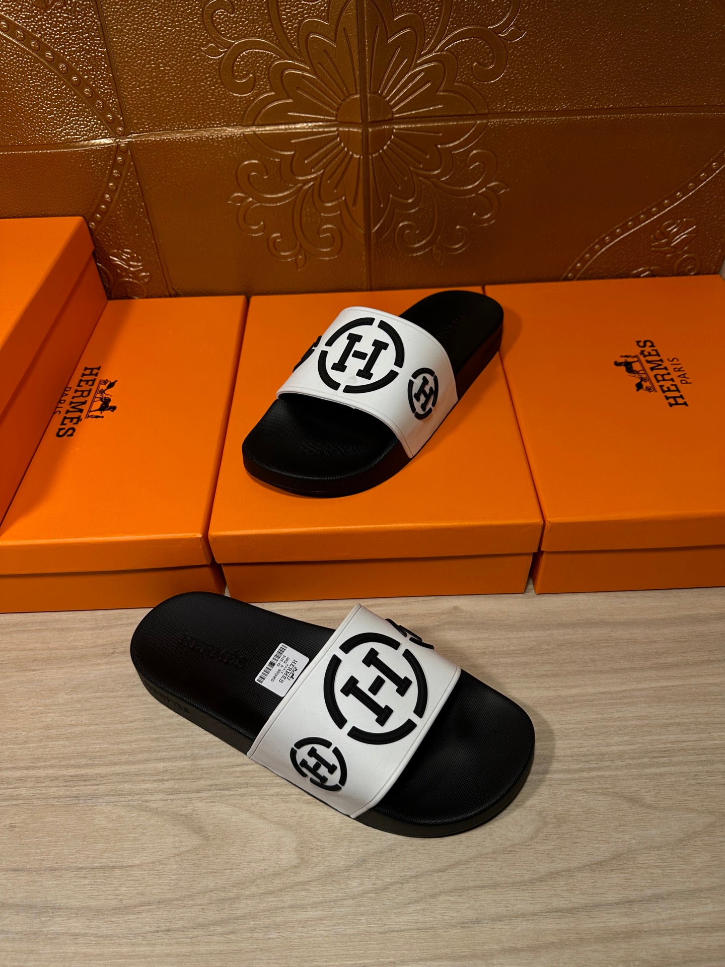 Pair of black slide sandals with white logo straps, one sandal upside-down