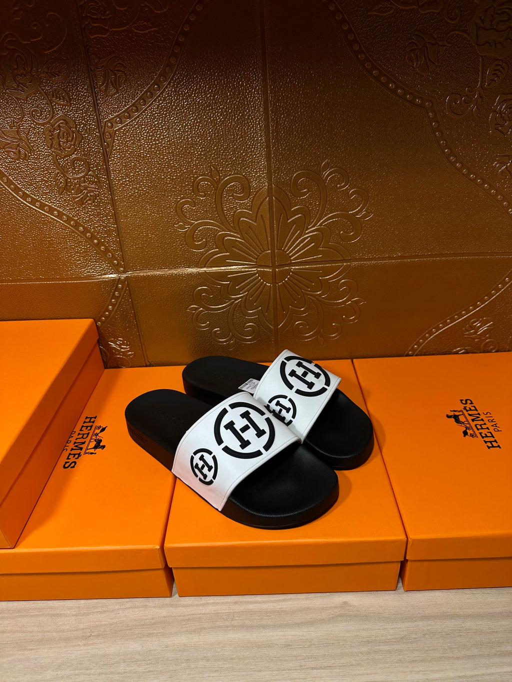 Black slide sandals with white logo strap, three-quarter front view