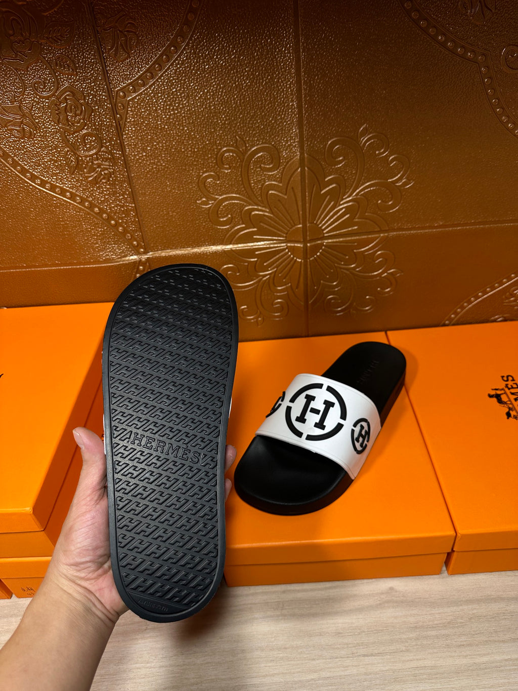 Black slide sandals with white logo strap; sole underside visible
