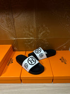 Black slide sandals with white logo strap, front angled view