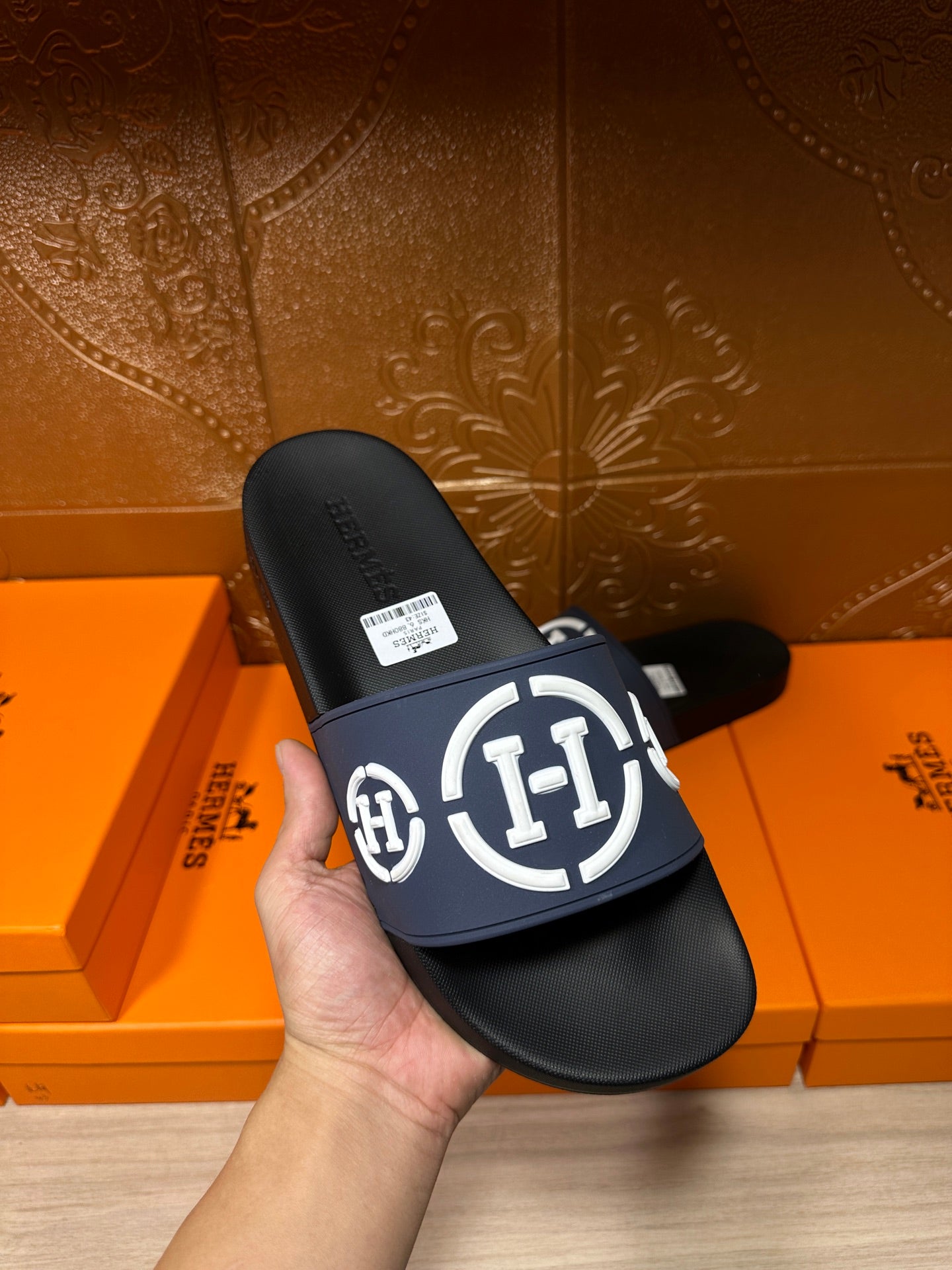 Handheld slide sandals: navy strap with white H logo over black footbed