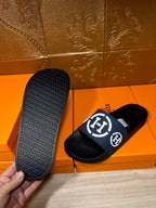 Slide sandals showing textured outsole and navy strap with white H logo