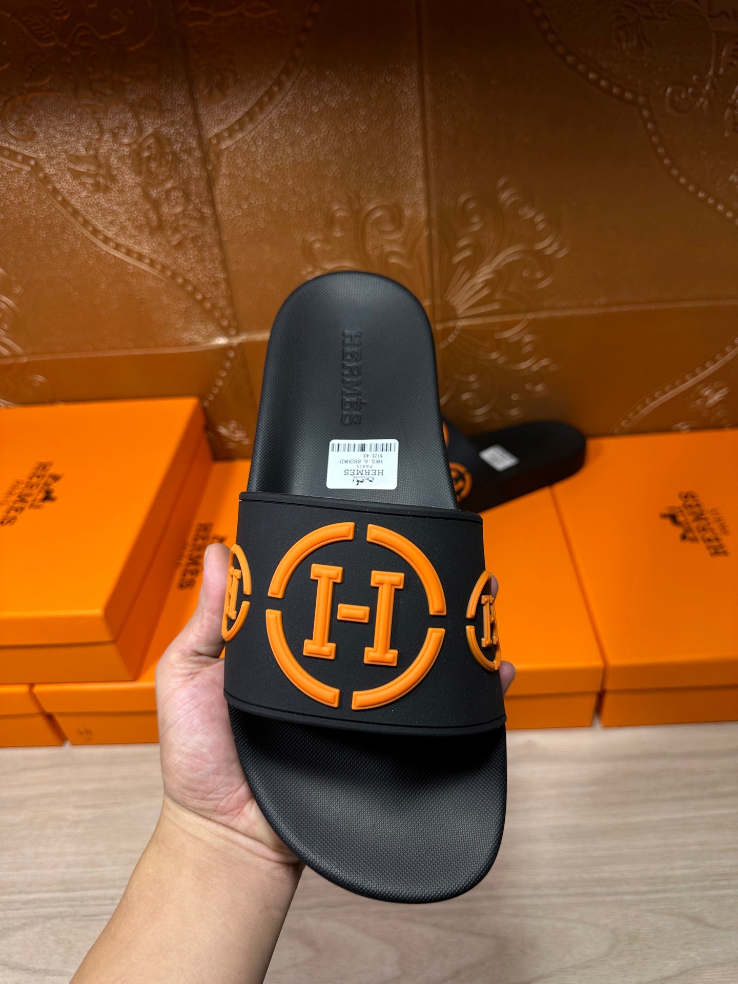 Hermes black slide sandal with orange logo strap detail, side view