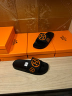 Hermes black slide sandals with orange logo straps, pair view