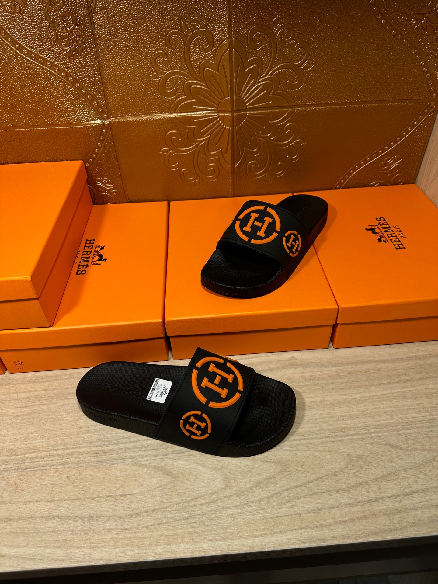 Hermes black slide sandals with orange logo straps, pair view