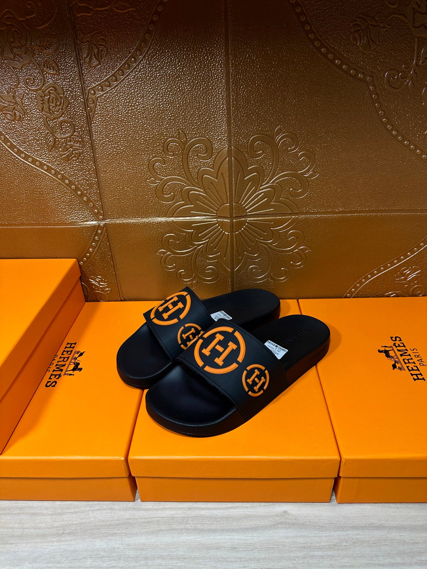 Hermes black slide sandals with orange logo detailing on straps