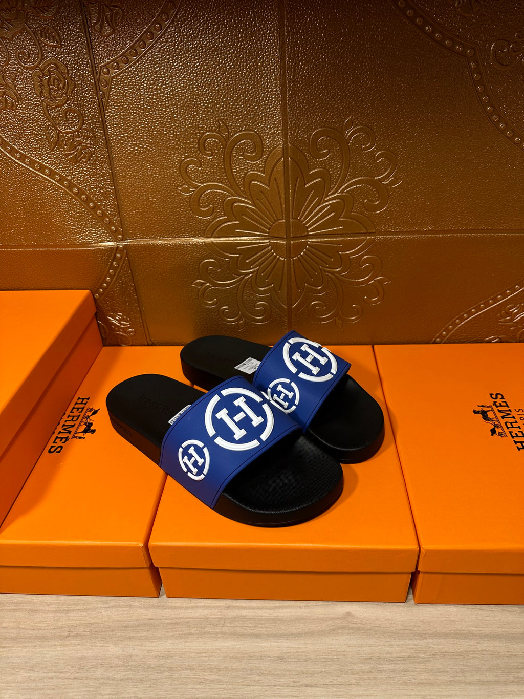 Pair of black slide sandals with blue logo straps and white emblems, side view