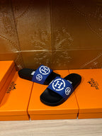 Black slide sandals with blue wide strap and white logos, two shoes shown