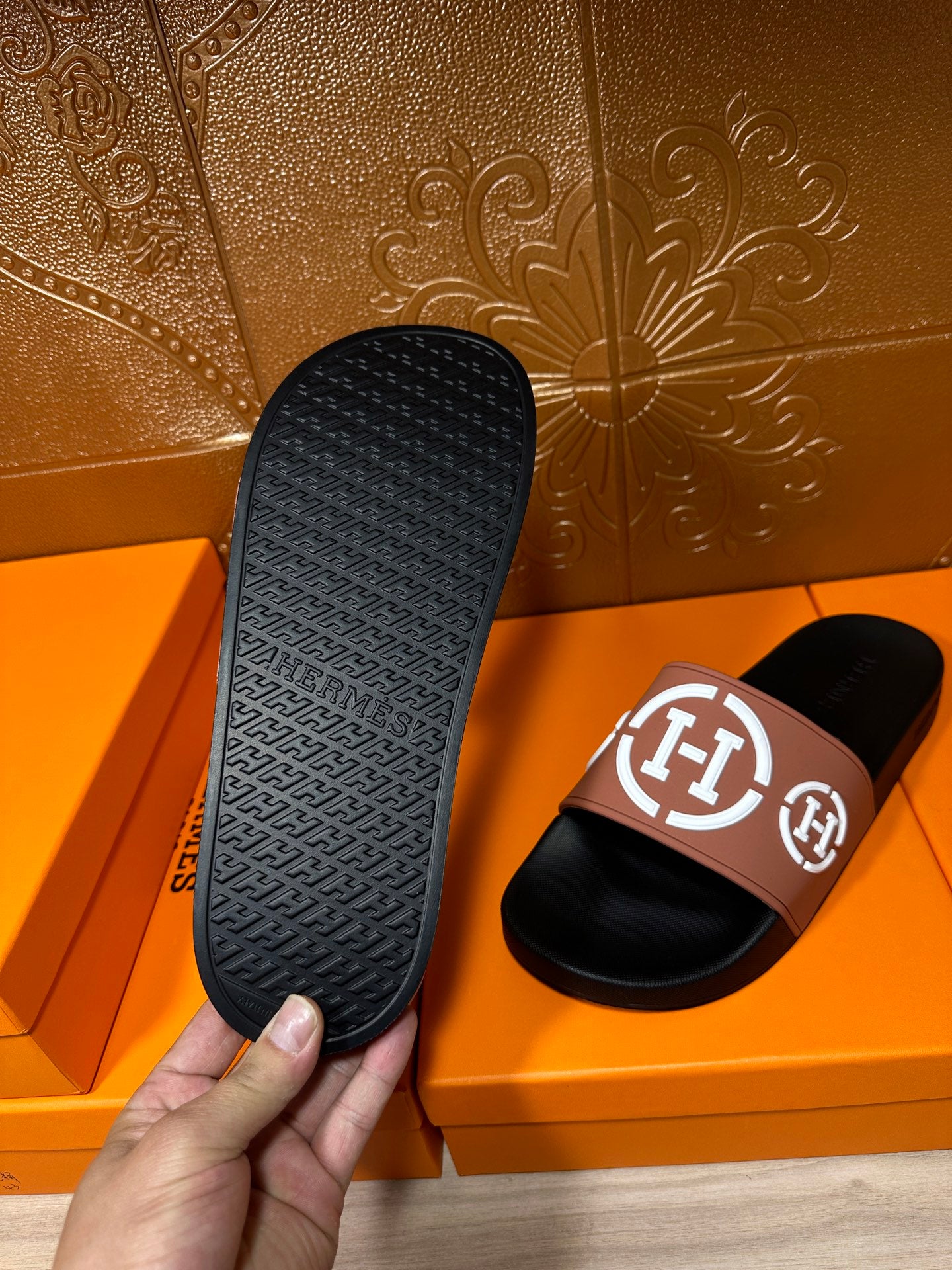 Hermes sandals outsole close-up: textured black sole and tan strap with H logo