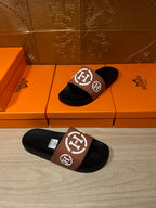 Hermes slide sandals with black footbeds and tan strap featuring white H logo