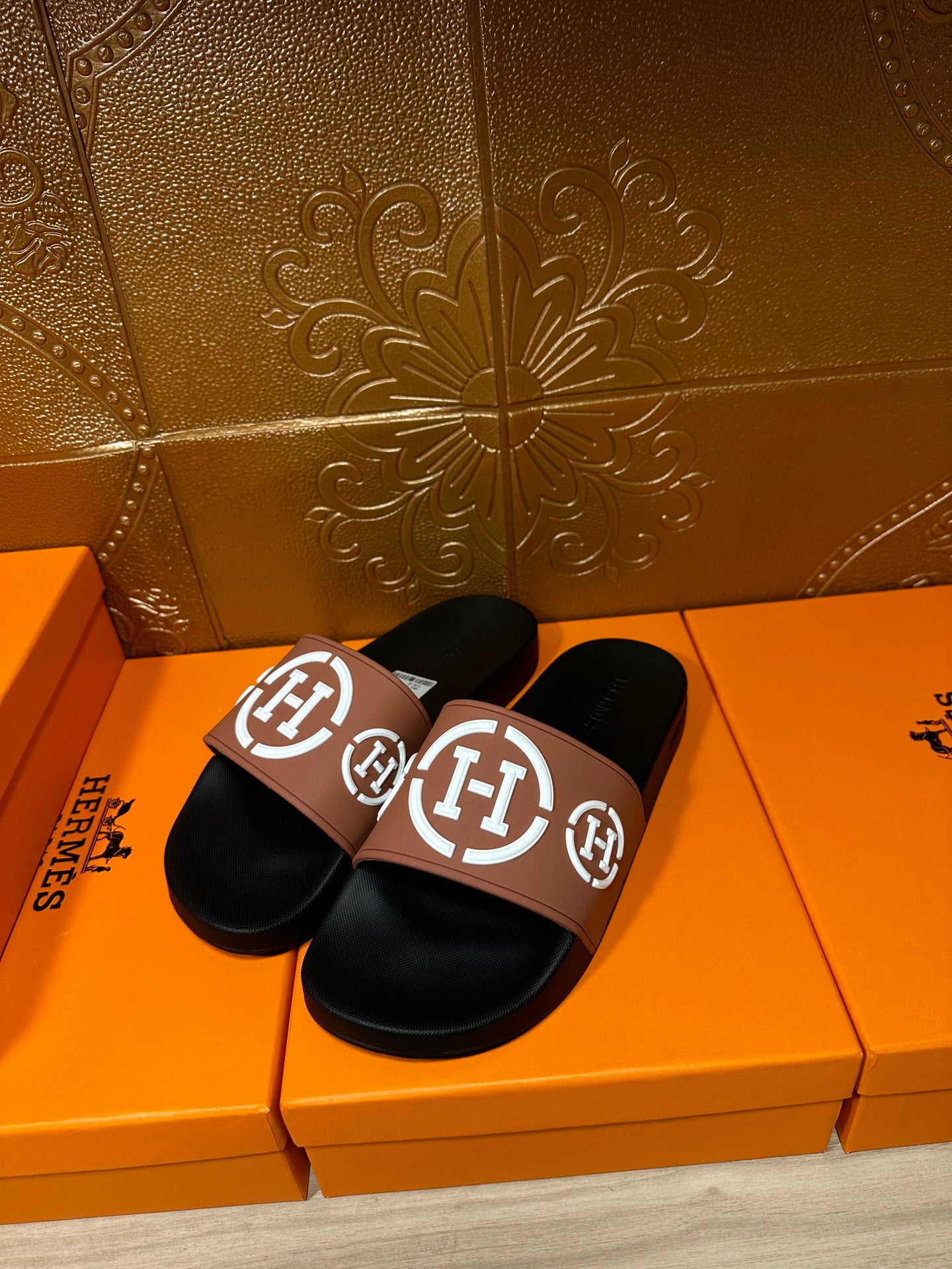 Hermes slide sandals with black soles and tan straps with white H logo detail