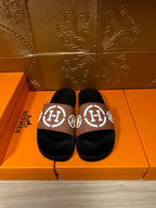Hermes sandals with black slide footbed and tan strap featuring white H logo