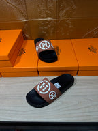 Hermes sandals on display: black slides with tan straps and white H logo