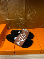 Hermes sandals in tan-and-black with white H logo on the slide strap