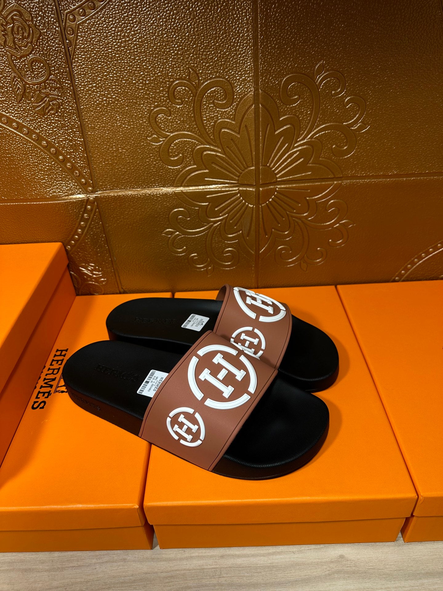 Hermes sandals in tan-and-black with white H logo on the slide strap