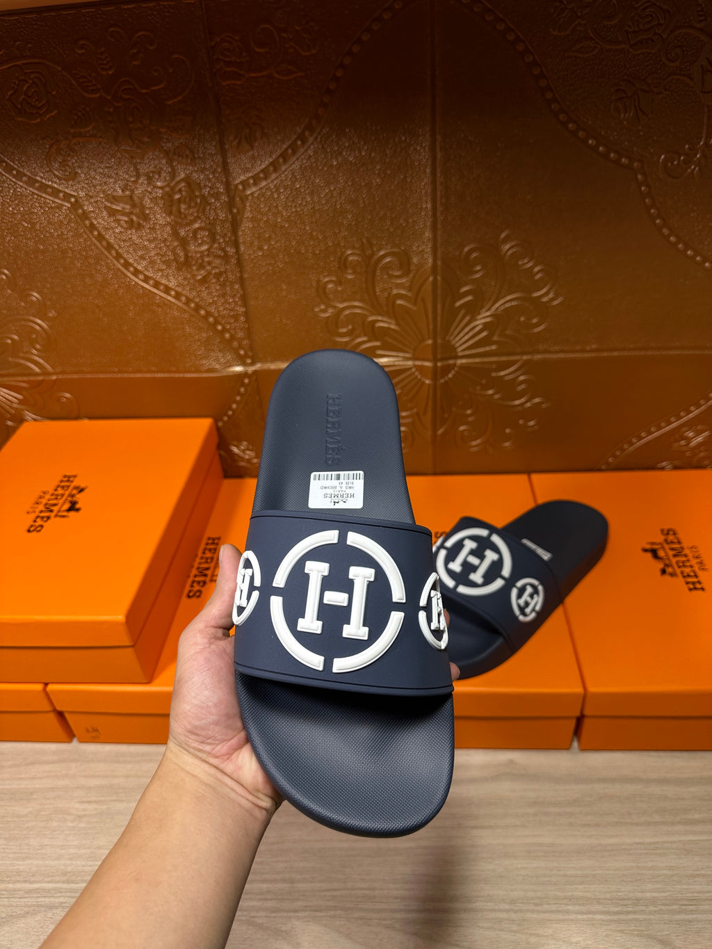 Dark slide sandal held up with textured footbed, wide strap with white emblem