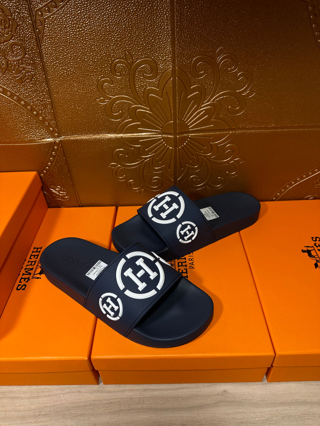 Dark slide sandals with front strap showing white emblem logos, pair