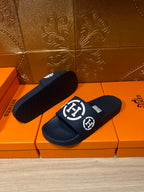 Dark slide sandals with white emblem logo on wide strap, one sole visible