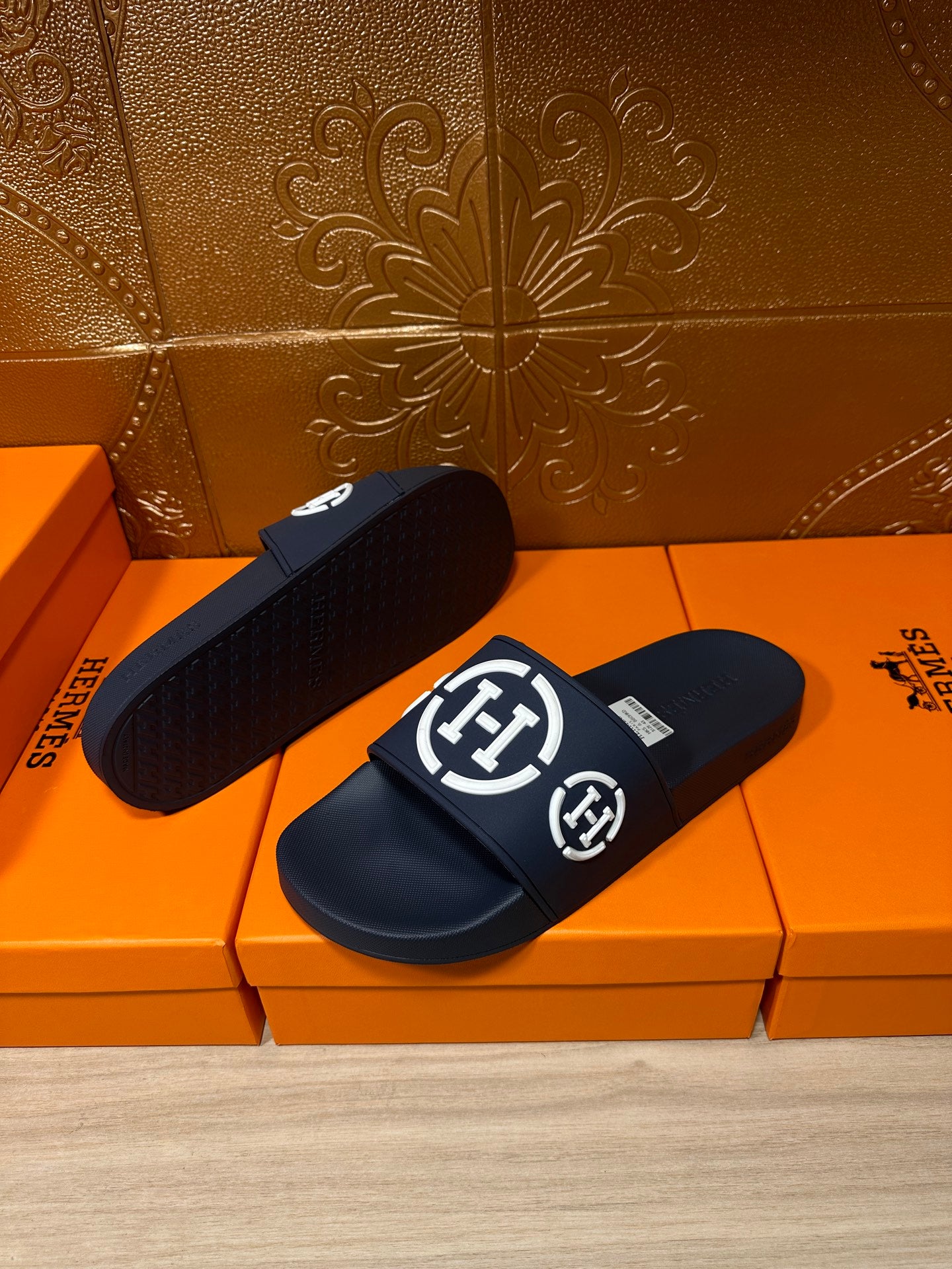 Dark slide sandals with white emblem logo on wide strap, one sole visible