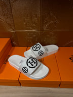 White slide sandals with black logo strap, side view